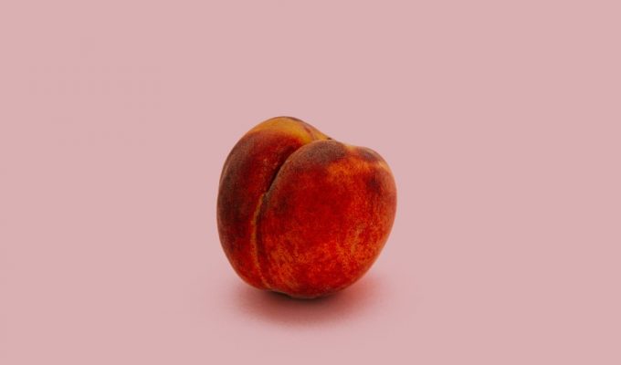 a peach sits on a blank background