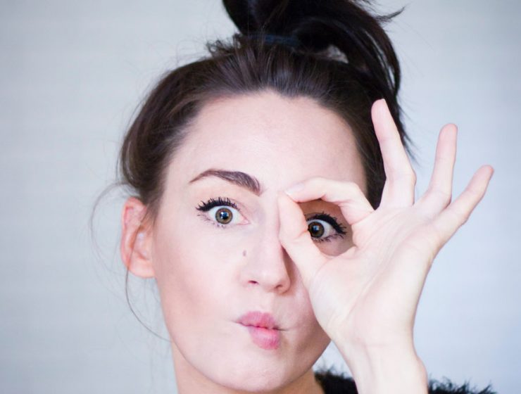 A woman holding her hand around one of her eyes to cover it up.