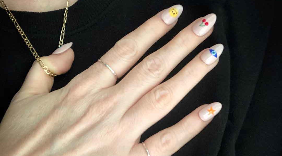 Lisa's hand with faux nail tips decorated emoji nail art.