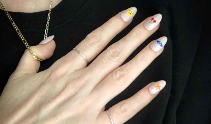 Lisa's hand with faux nail tips decorated emoji nail art.