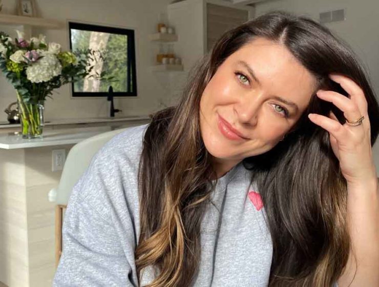 Victoria Radford smiles, tilting her head as she pulls her hair out of her face.