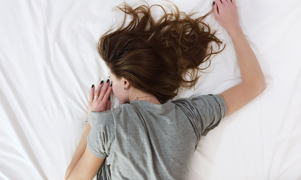A woman lying in bed, not feeling so hot.