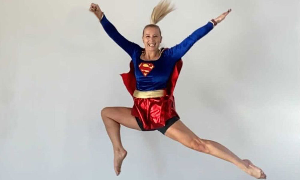 Writer and runner Heather Gardner jumping in the air, wearing her Supergirl run costume.