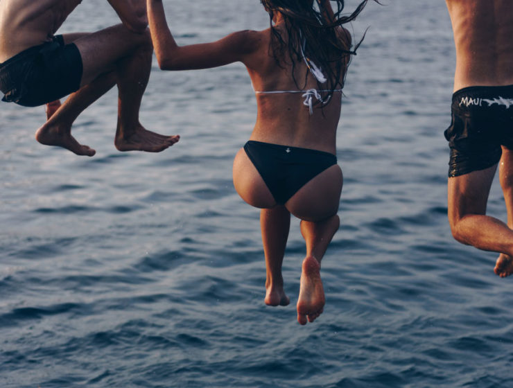 Three friends are mid-air as they're jumping into a freezing cold lake