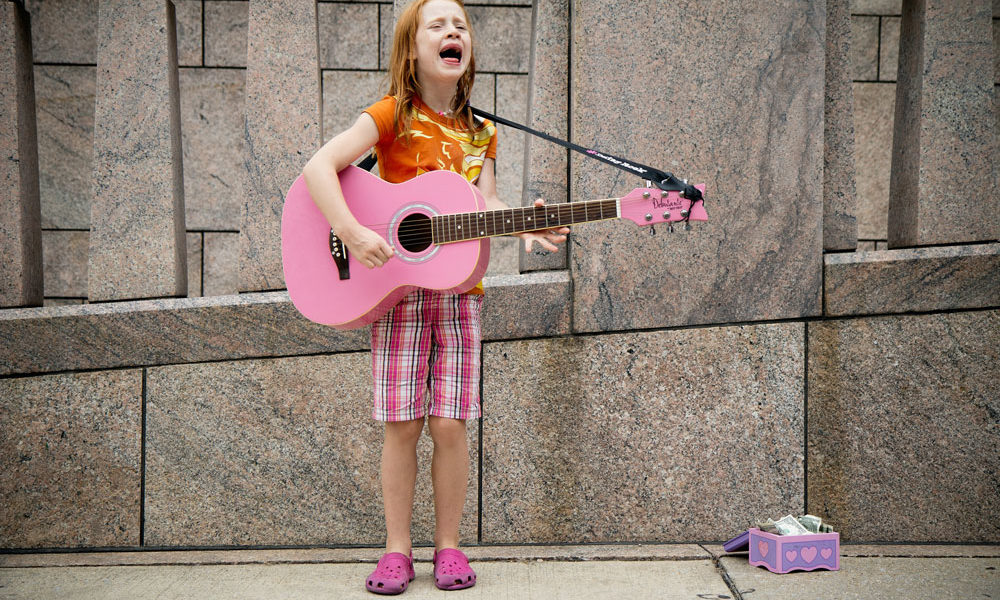 An adorable red-haired little girl, playing a guitar and singing her heart out!