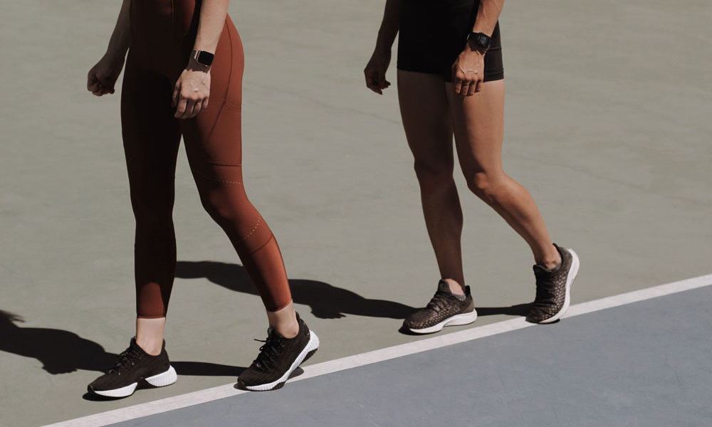 Two women in athletic wear walking around a track