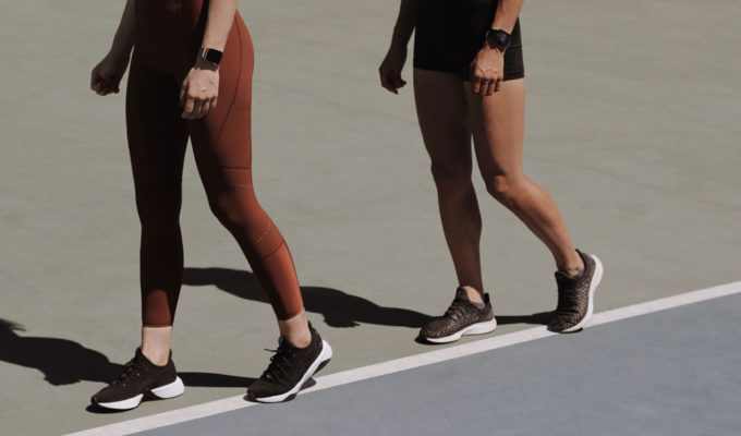 Two women in athletic wear walking around a track