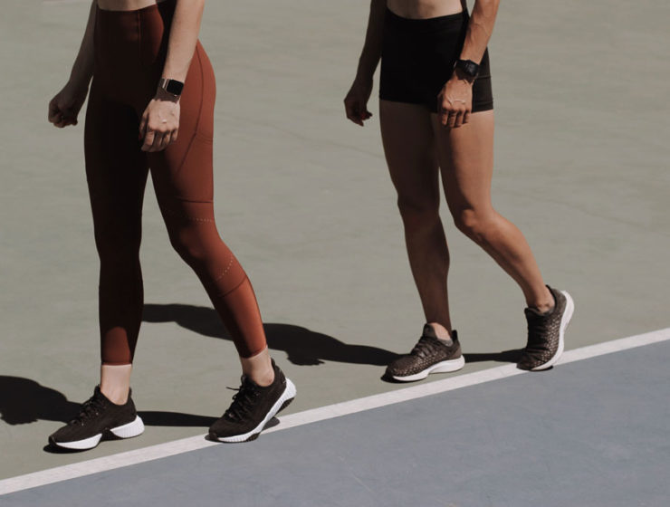 Two women in athletic wear walking around a track