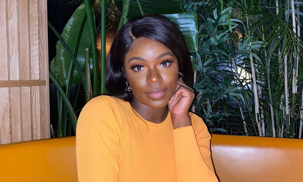 Joelle Kabisoso has her hand on her cheek as she smiles confidently