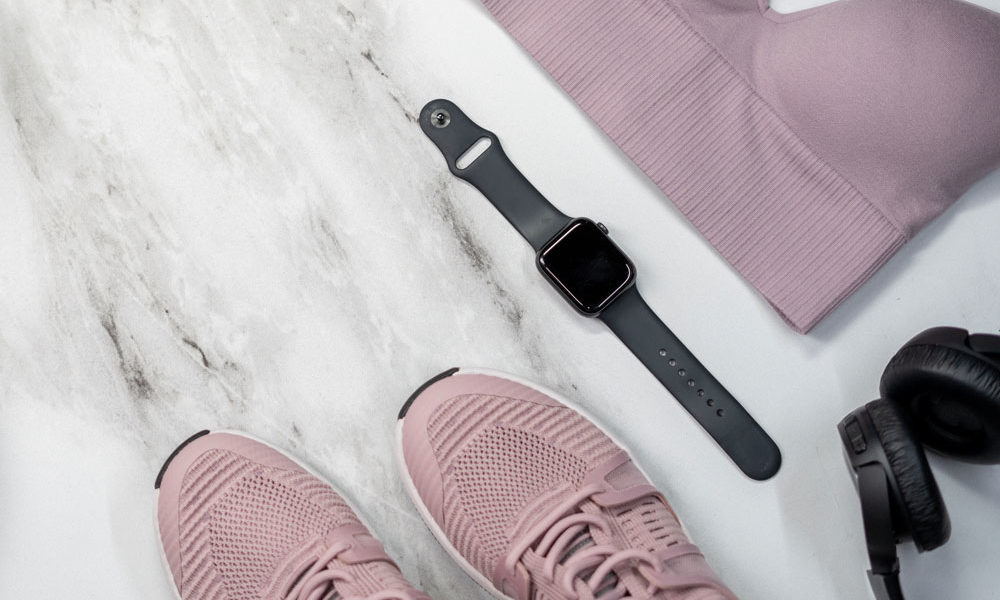 A flat lay of a sports bra, running shoes, earphones and of course an Apple Watch