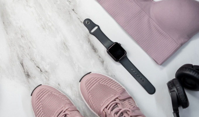 A flat lay of a sports bra, running shoes, earphones and of course an Apple Watch