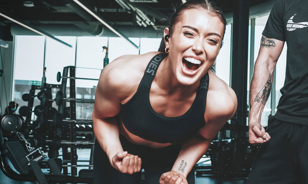 A woman with an injury is pumped after her workout, smiling and flexing with pride, in working out despite her injuries.