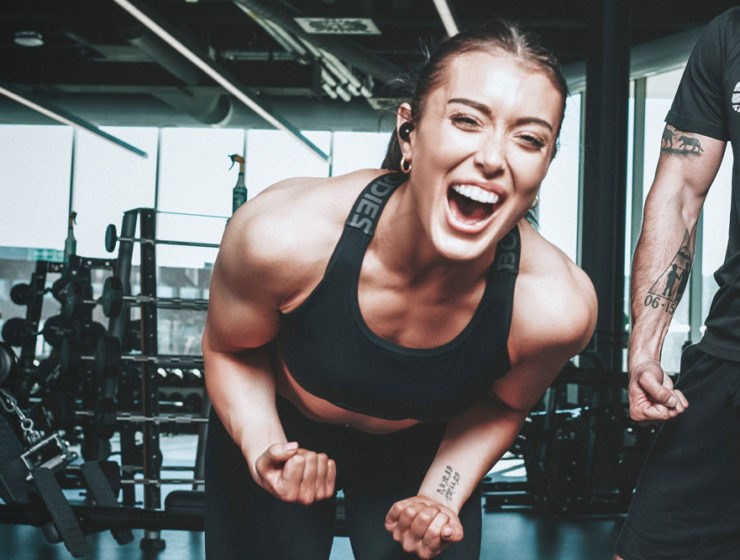 A woman with an injury is pumped after her workout, smiling and flexing with pride, in working out despite her injuries.