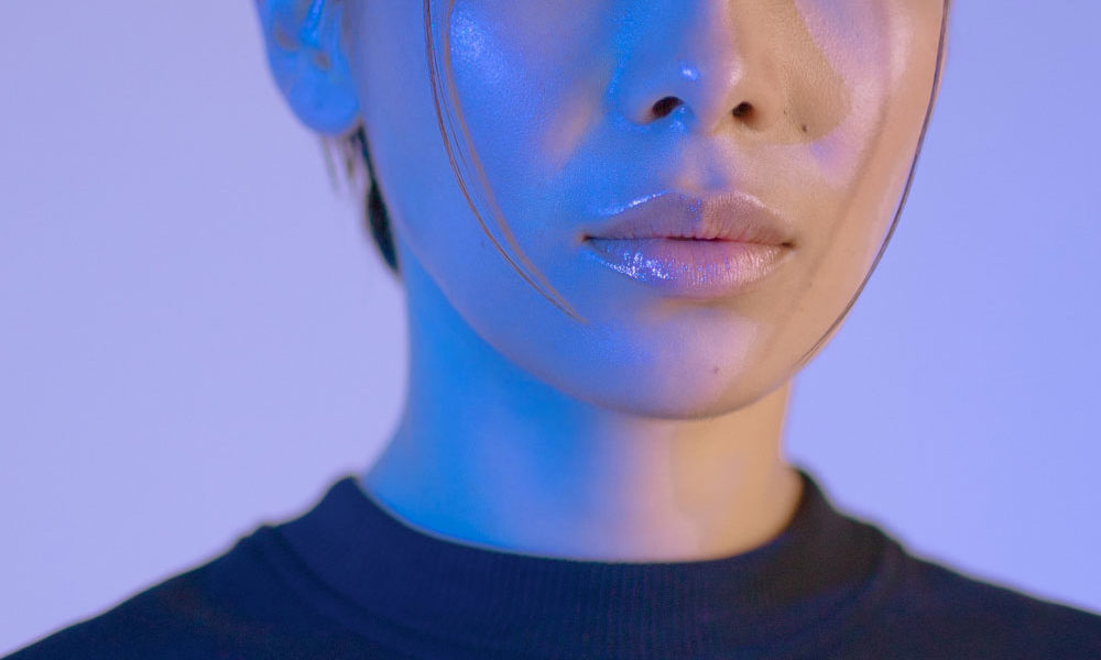 A woman with shiny cheeks and lips, looking well hydrated and glossy.