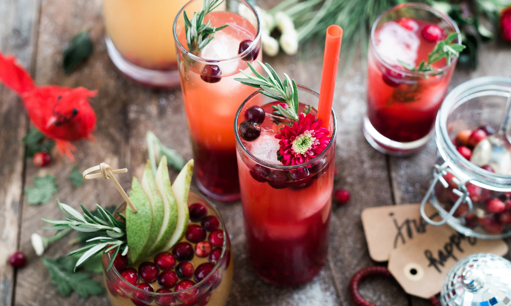 A tableful of fresh cocktails garnished for the holidays with herbs