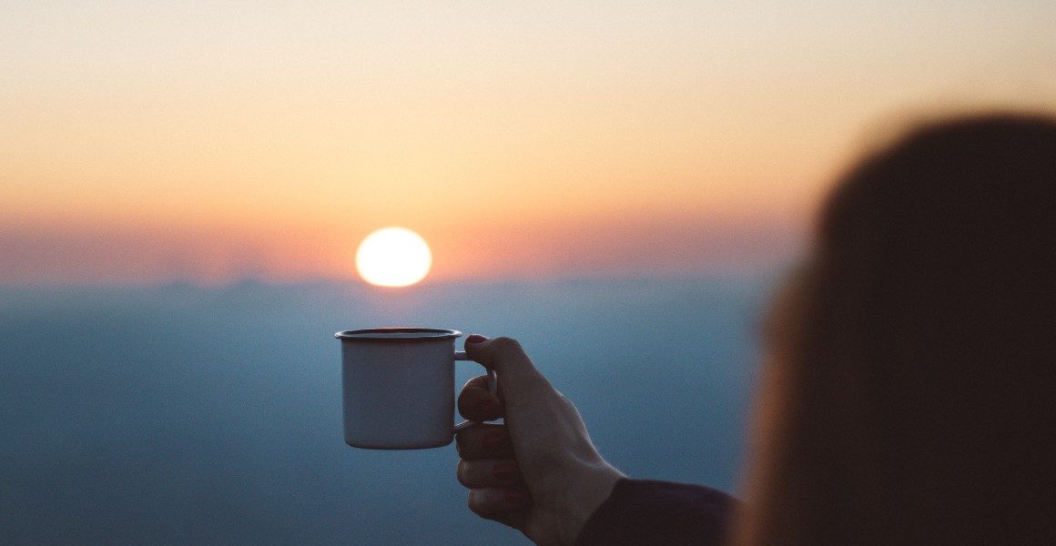 woman holding cup toward the sun