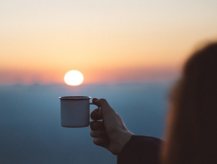 woman holding cup toward the sun