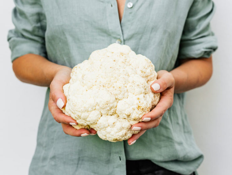 Woman holds a head of cauliflower, ready for David Rocco's Cauliflower Putannesca recipe