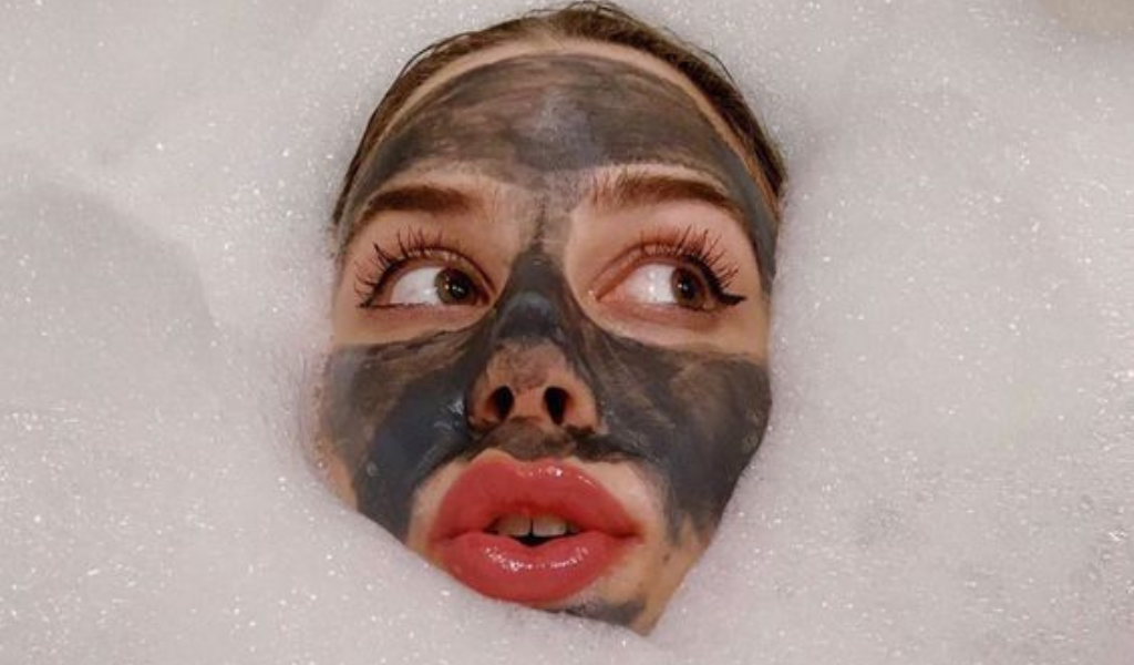 woman in bath with bubbles around her face with a mud mask on as we cover a mud treatment