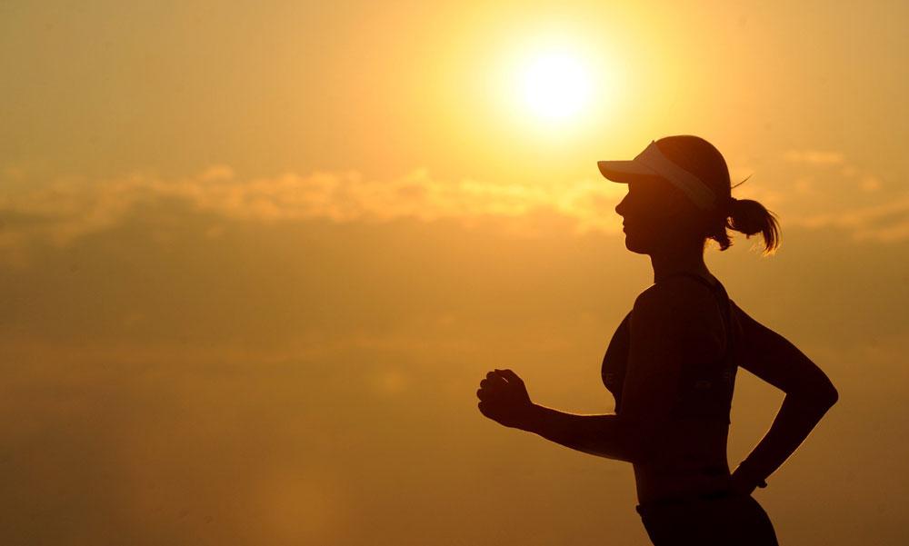 A woman running in the sun, as we cover exercising in the heat and what you should know.