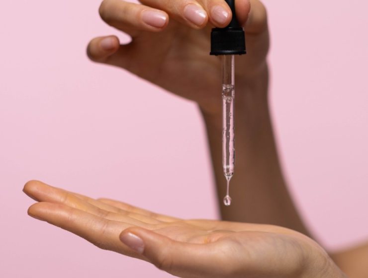 woman holding serum dropper in hands