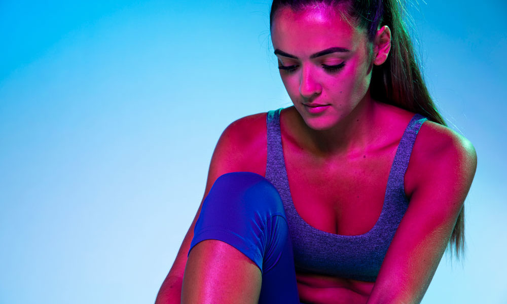 A woman tying up her monochromatic shoes.
