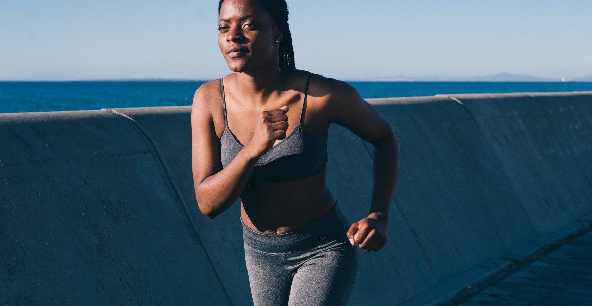 woman running beside breakwall