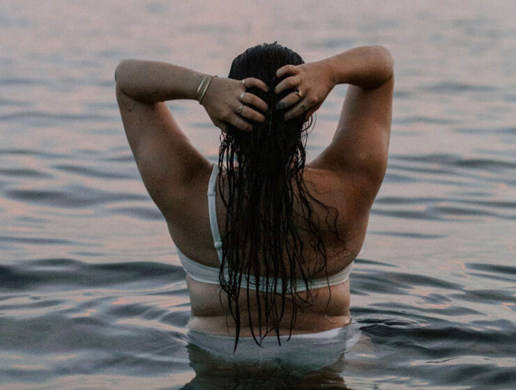 Woman in the ocean, staring out, wanting to keep that summer feeling all year long.